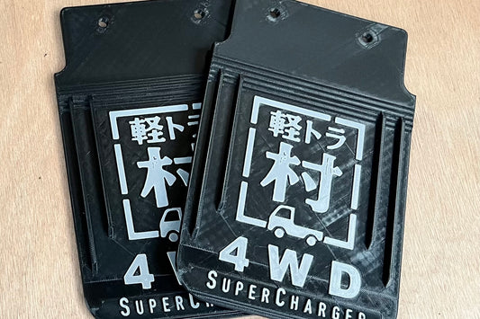 軽トラ村ロゴのマッドガード左右2枚。ブラックの本体にグレーの立体文字